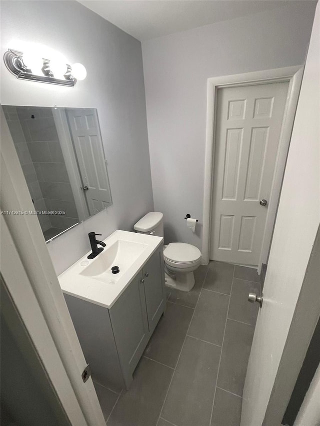 bathroom with tile patterned flooring, vanity, and toilet