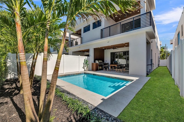 back of house with a fenced in pool, a lawn, ceiling fan, a patio, and a balcony