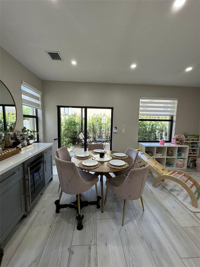 dining space with a wealth of natural light, beverage cooler, and light hardwood / wood-style floors