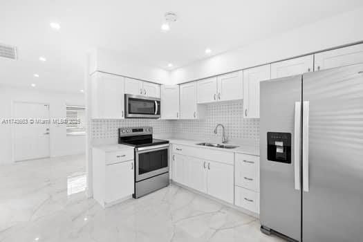 1431-1433 N 14th Way, Hollywood, FL 33020 - kitchen with appliances with stainless steel finishes, light marble finish floors, light countertops, white cabinetry, and recessed lighting