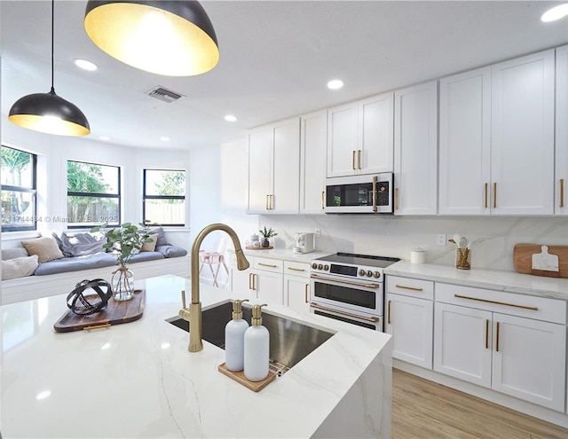 kitchen featuring pendant lighting, white appliances, white cabinets, and light stone countertops