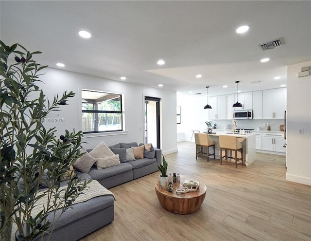 living area featuring recessed lighting, visible vents, light wood-style flooring, and baseboards