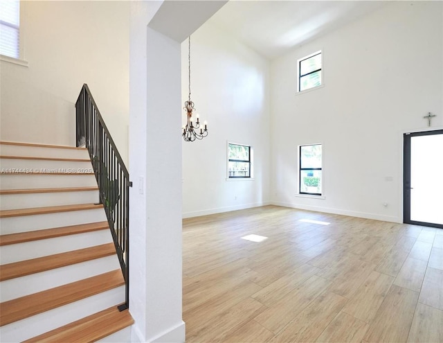 stairs featuring a chandelier, wood finished floors, a wealth of natural light, and baseboards