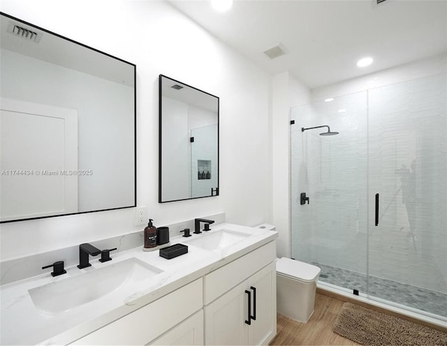 full bath with toilet, wood finished floors, a sink, and visible vents