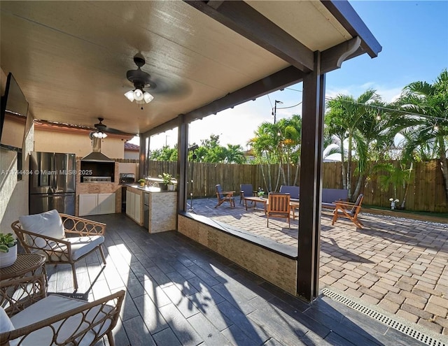 view of patio featuring a fenced backyard, ceiling fan, an outdoor living space, and an outdoor kitchen