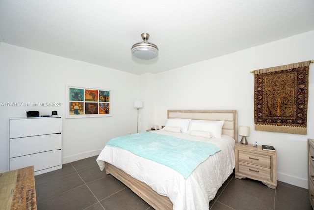 bedroom with baseboards and dark tile patterned floors