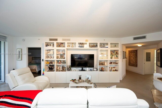 living room featuring a textured ceiling, visible vents, and electric panel