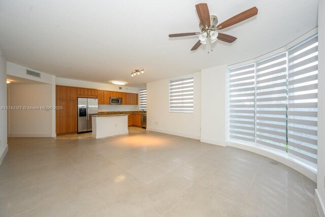unfurnished living room featuring light tile patterned floors, baseboards, ceiling fan, and visible vents