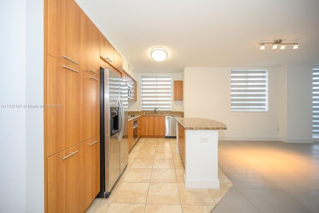 kitchen featuring stone counters, a sink, appliances with stainless steel finishes, a center island, and light tile patterned floors