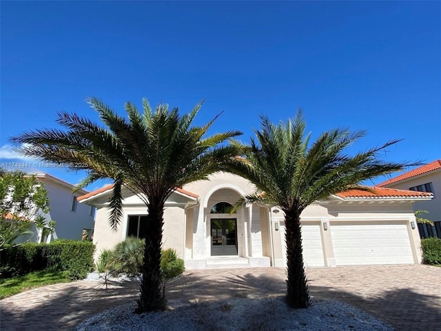 view of front of house featuring an attached garage, decorative driveway, and stucco siding