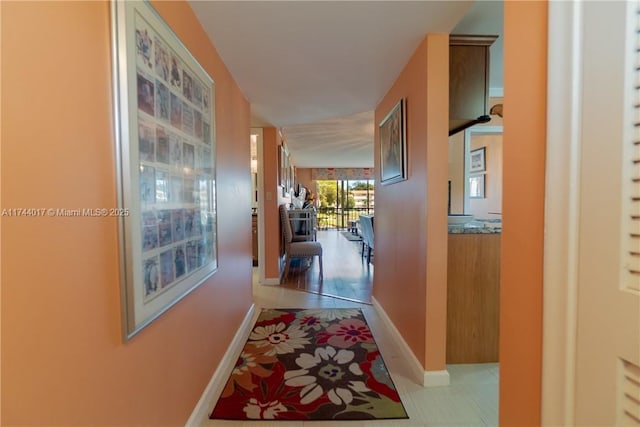 hall featuring baseboards and light tile patterned floors