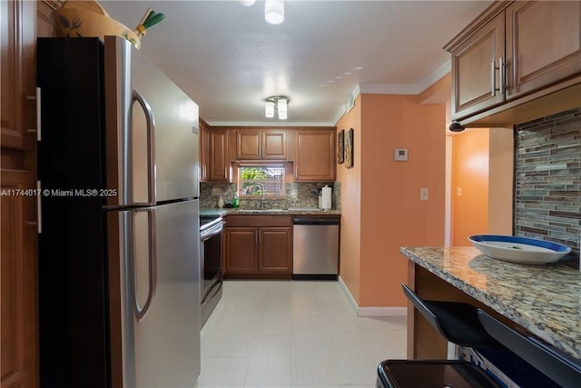 kitchen featuring appliances with stainless steel finishes, brown cabinets, decorative backsplash, and light stone counters