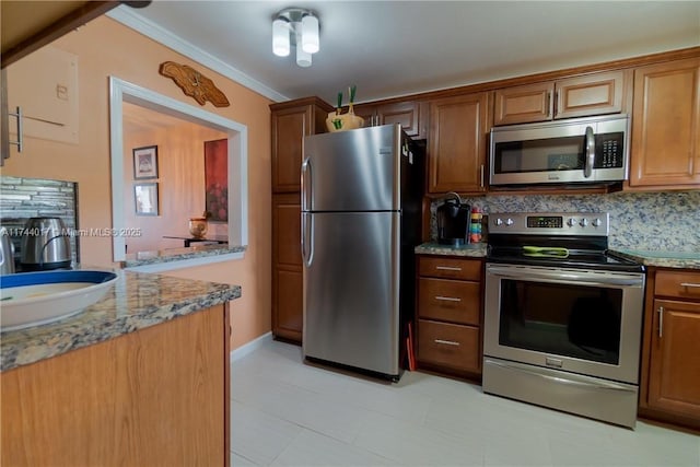 kitchen featuring light stone counters, stainless steel appliances, a sink, backsplash, and brown cabinetry