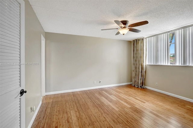 empty room with light wood finished floors, baseboards, a ceiling fan, and a textured ceiling