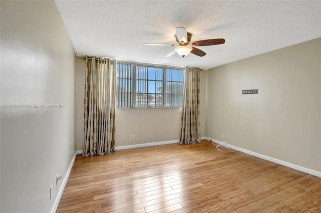 unfurnished room with light wood finished floors, ceiling fan, baseboards, and a textured ceiling