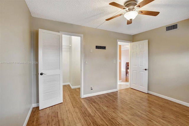 unfurnished bedroom with a spacious closet, light wood-style flooring, visible vents, and baseboards