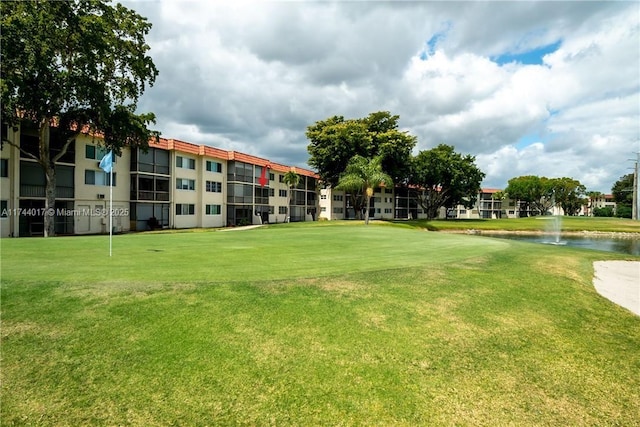 view of property's community with a water view and a lawn