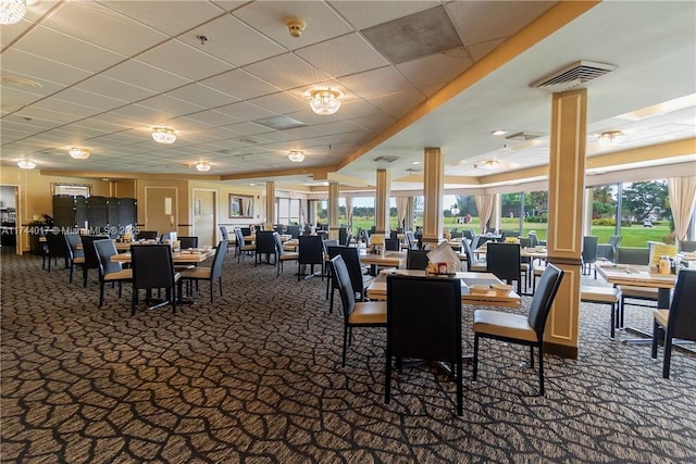 carpeted dining space featuring visible vents, a paneled ceiling, and decorative columns