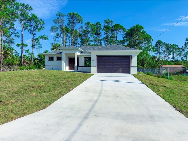 view of front of house featuring driveway, an attached garage, fence, a front lawn, and stucco siding