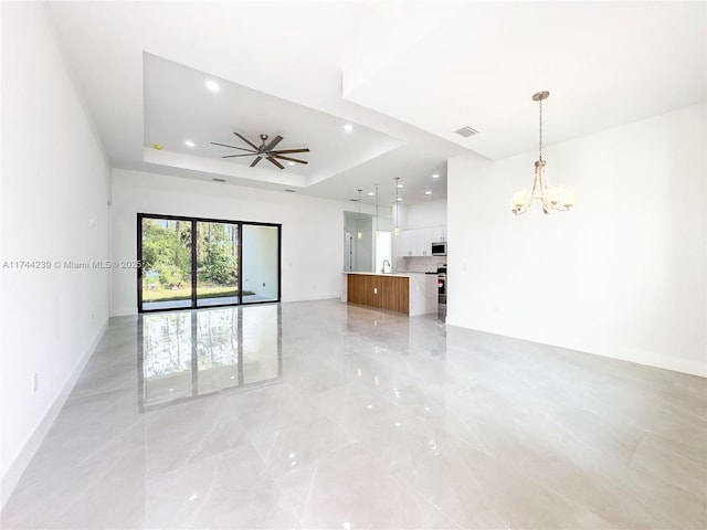 spare room featuring sink, a tray ceiling, and ceiling fan with notable chandelier