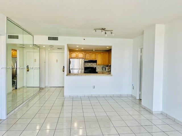 1470 NE 123rd St Unit A707, North Miami, FL 33161 - kitchen featuring backsplash, brown cabinetry, visible vents, and appliances with stainless steel finishes