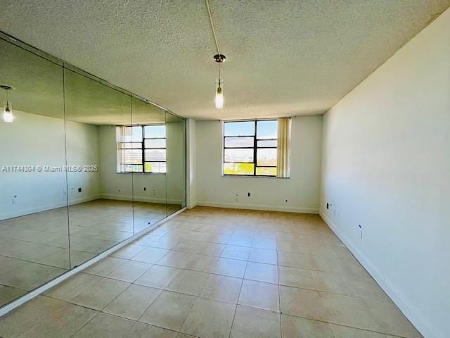 1470 NE 123rd St Unit A707, North Miami, FL 33161 - unfurnished bedroom featuring light tile patterned flooring, a closet, a textured ceiling, and baseboards