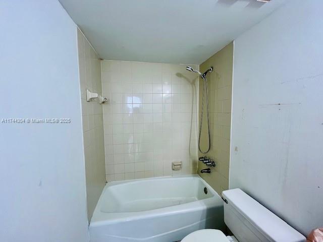 bathroom featuring tiled shower / bath combo and toilet