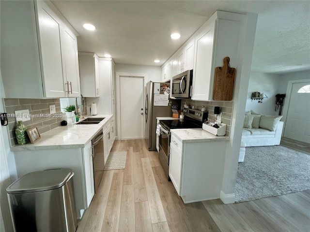 kitchen with white cabinetry, tasteful backsplash, stainless steel appliances, and light hardwood / wood-style floors