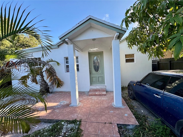 entrance to property featuring fence and stucco siding