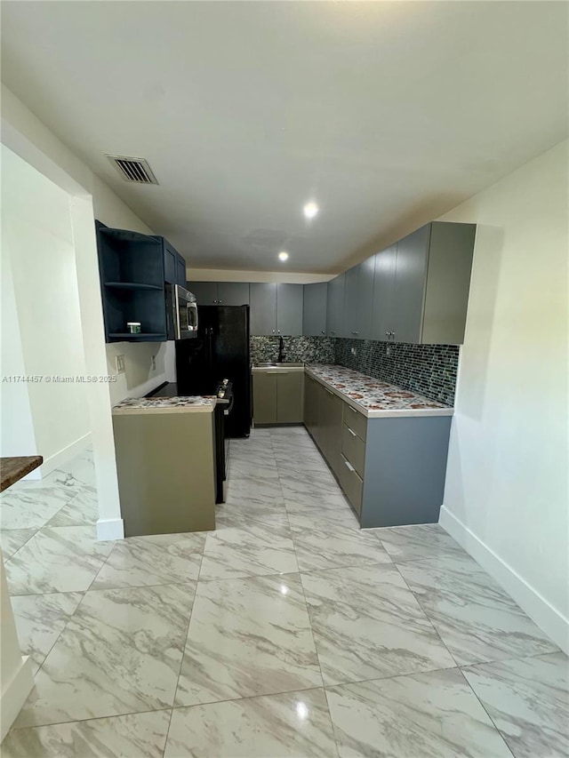 kitchen with stainless steel microwave, backsplash, visible vents, and gray cabinetry