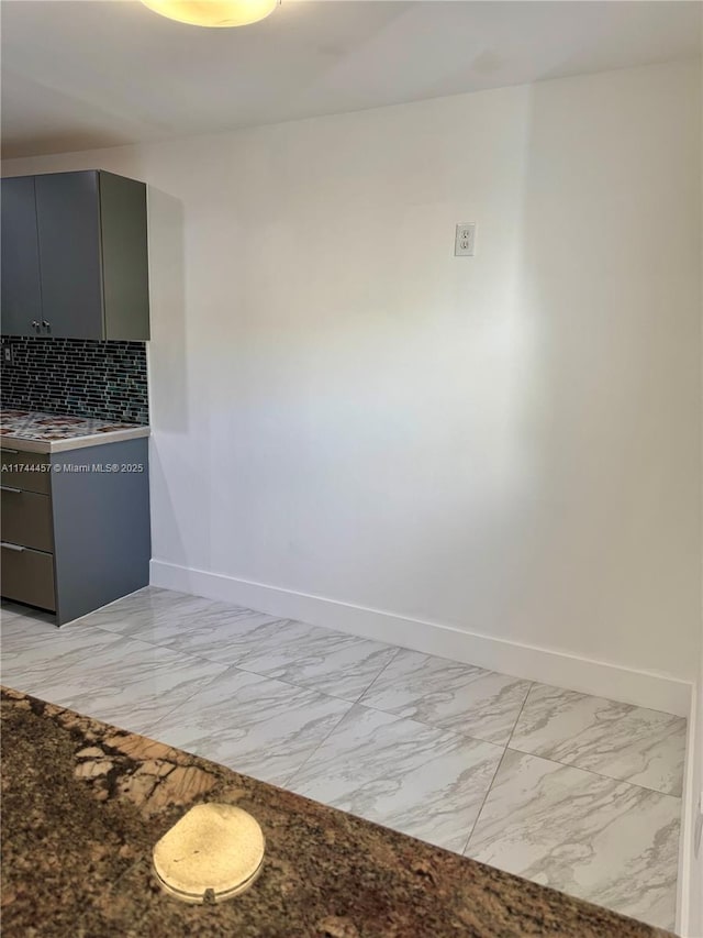 kitchen with gray cabinets, marble finish floor, backsplash, and baseboards