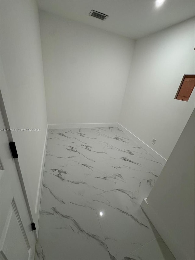 unfurnished room with marble finish floor, visible vents, and baseboards