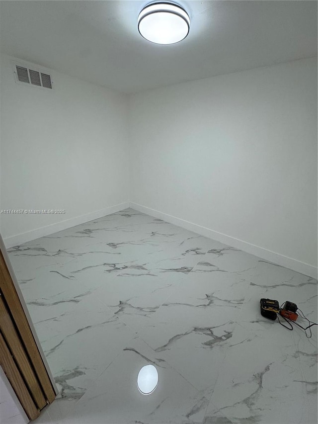 empty room with marble finish floor, visible vents, and baseboards