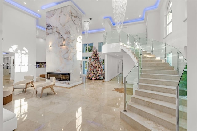 stairway with a towering ceiling, ornamental molding, and a premium fireplace