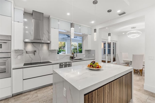 kitchen featuring white cabinetry, wall chimney range hood, stainless steel appliances, and sink