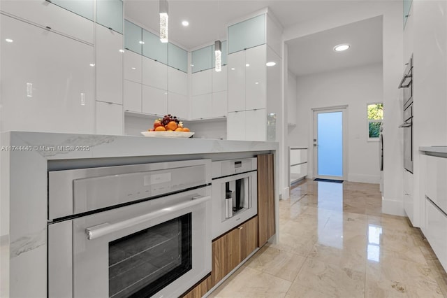 kitchen with oven, white cabinets, a high ceiling, hanging light fixtures, and wall oven