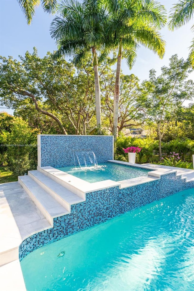 view of pool with a hot tub