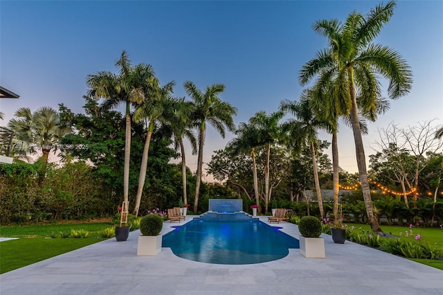 pool at dusk featuring a grill, a patio area, and a lawn