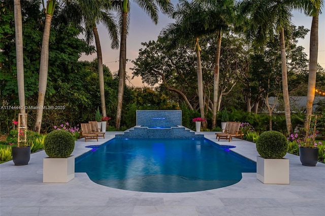 pool at dusk with a patio area