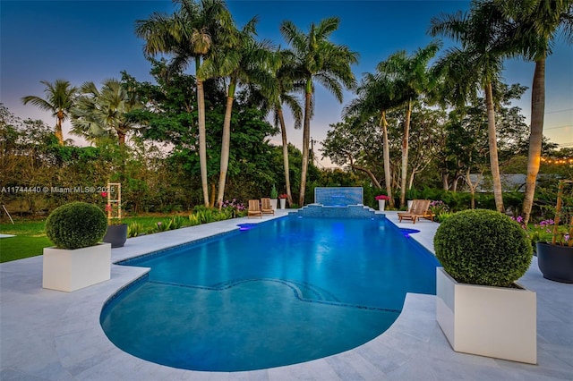 pool at dusk featuring a patio