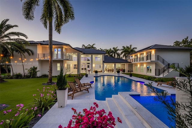 pool at dusk with a yard, a jacuzzi, and a patio area