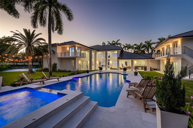 pool at dusk with a yard and a patio