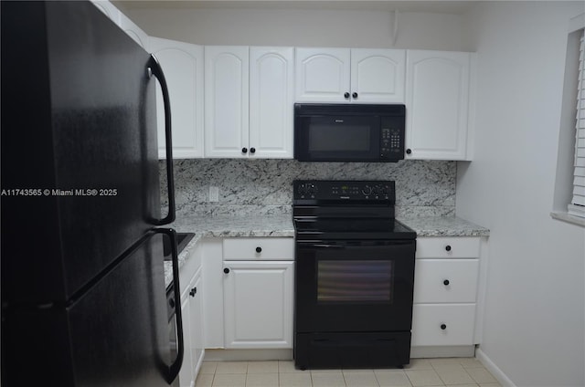 kitchen featuring tasteful backsplash, black appliances, light tile patterned floors, light stone countertops, and white cabinets