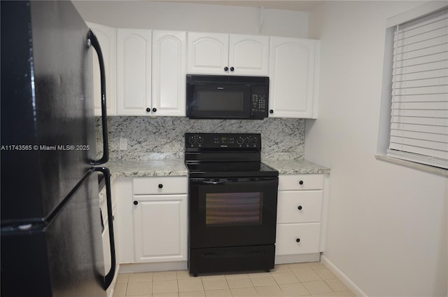 kitchen with white cabinetry, light stone counters, black appliances, light tile patterned floors, and backsplash