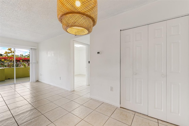 interior space with access to outside, light tile patterned floors, a textured ceiling, and a closet