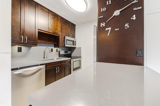 kitchen featuring stainless steel appliances, dark brown cabinets, sink, and a textured ceiling