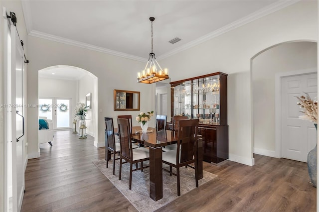 dining space featuring ornamental molding, a barn door, and dark wood-type flooring