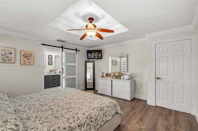 bedroom featuring hardwood / wood-style flooring, ornamental molding, and a barn door