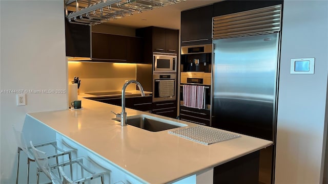 17001 Collins Ave Unit 2702, Sunny Isles Beach, FL 33160 - kitchen featuring built in appliances, a sink, light countertops, a kitchen breakfast bar, and a peninsula
