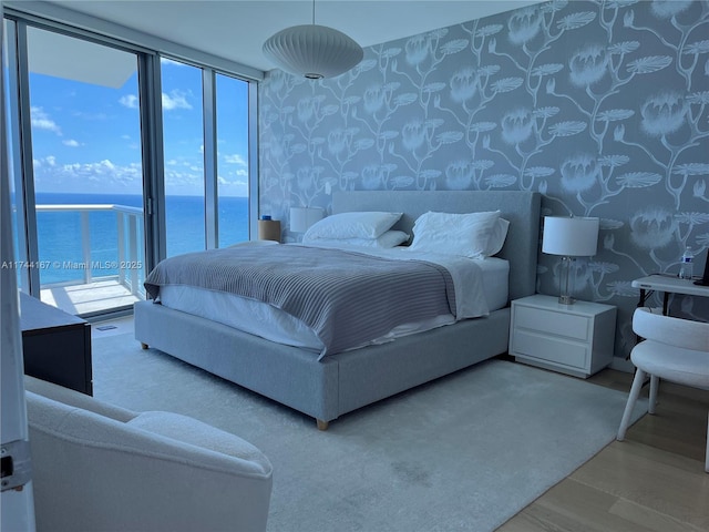 17001 Collins Ave Unit 2702, Sunny Isles Beach, FL 33160 - bedroom featuring wallpapered walls, a water view, wood finished floors, floor to ceiling windows, and access to outside